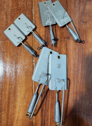 Six trolling planers in three sizes laid out on a boat covering board for kingfish, wahoo, and tuna fishing